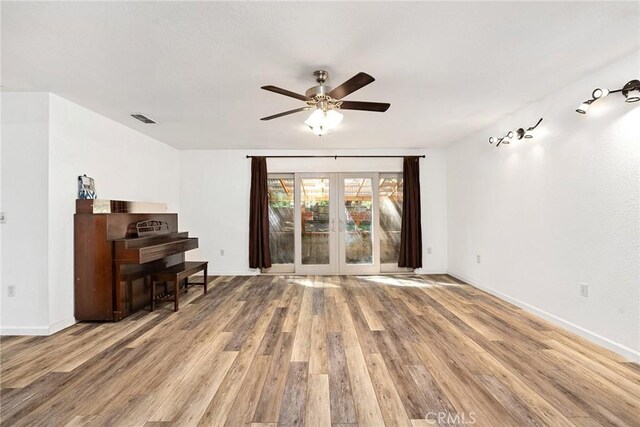 living room featuring visible vents, baseboards, a ceiling fan, light wood-style floors, and french doors