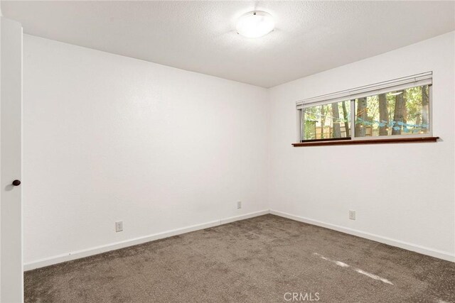 carpeted spare room featuring baseboards