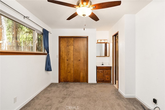 unfurnished bedroom featuring light carpet, a closet, ensuite bath, and ceiling fan