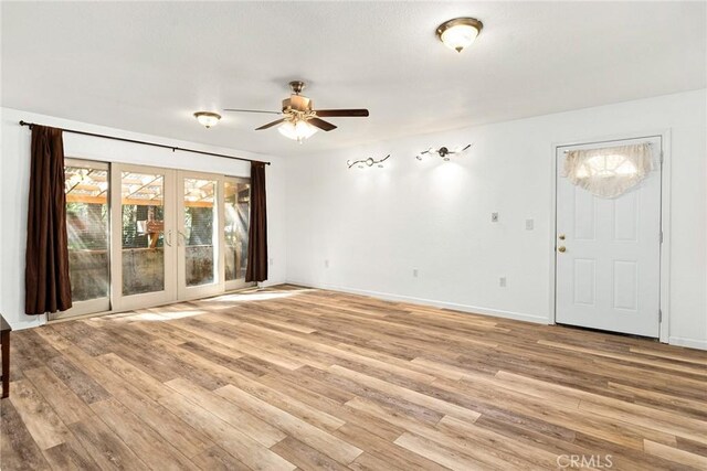 unfurnished living room featuring light wood-type flooring, french doors, ceiling fan, and baseboards