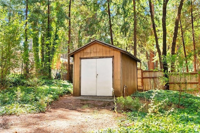 view of shed with a wooded view and fence