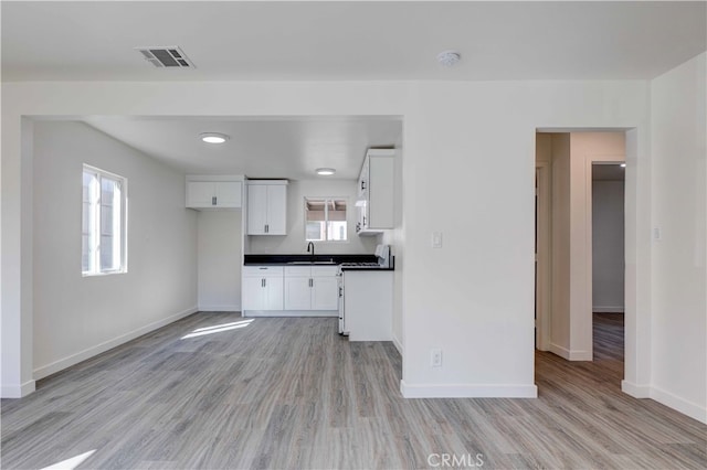 kitchen with light wood-type flooring, white cabinetry, plenty of natural light, and sink