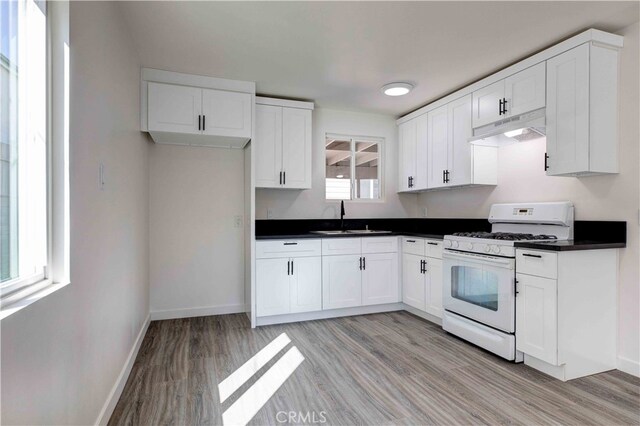 kitchen with white cabinets, white range with gas stovetop, sink, and light hardwood / wood-style flooring