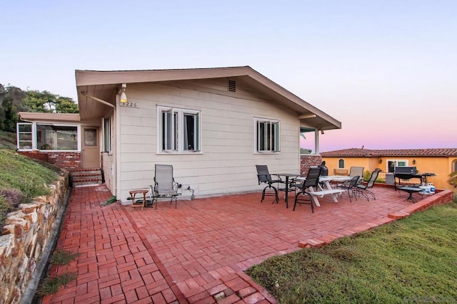 back house at dusk with a patio area