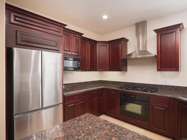 kitchen featuring light tile patterned floors, wall chimney range hood, dark stone counters, and black appliances