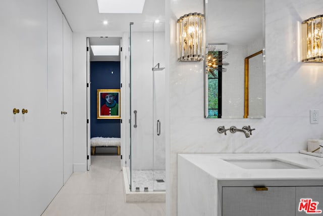 bathroom with vanity, a skylight, a shower with shower door, and tile patterned flooring