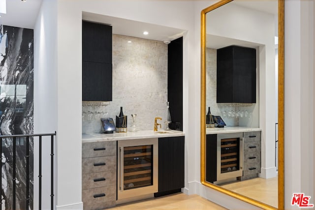 bar featuring beverage cooler, sink, and tasteful backsplash