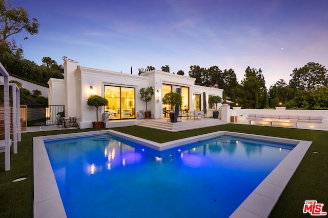 pool at dusk with a patio area