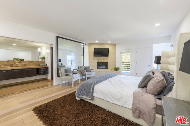 bedroom with a large fireplace and hardwood / wood-style flooring