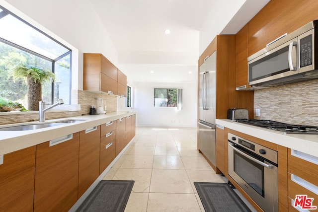 kitchen with stainless steel appliances, sink, a healthy amount of sunlight, and tasteful backsplash