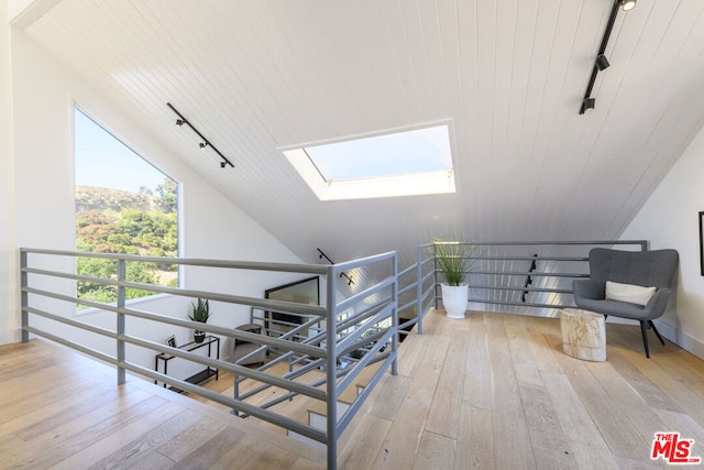 staircase with wood-type flooring, track lighting, wooden ceiling, and lofted ceiling with skylight