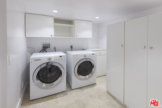 clothes washing area with washing machine and clothes dryer and cabinets