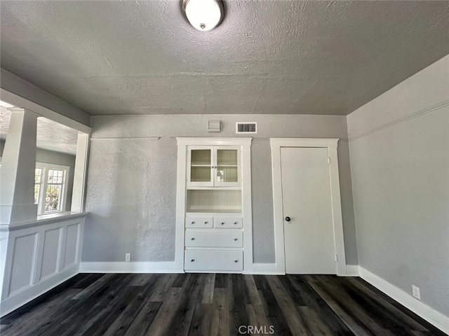 interior space with a textured ceiling and dark hardwood / wood-style flooring