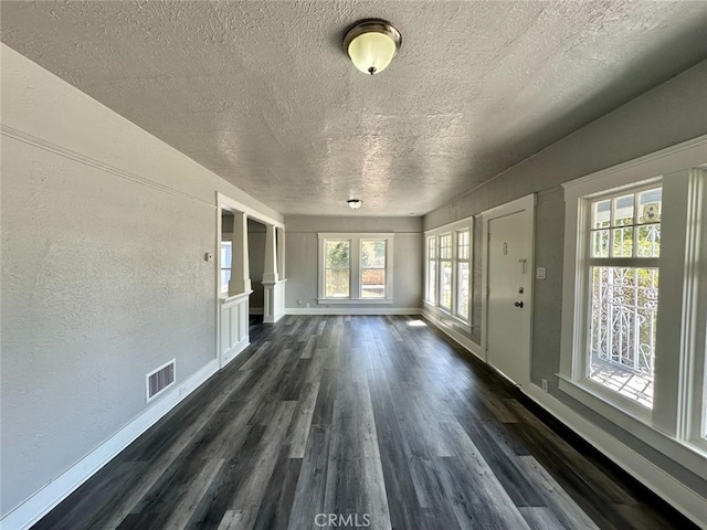 unfurnished living room with a textured ceiling and dark hardwood / wood-style floors