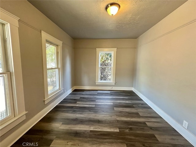 unfurnished room with a textured ceiling and dark hardwood / wood-style flooring