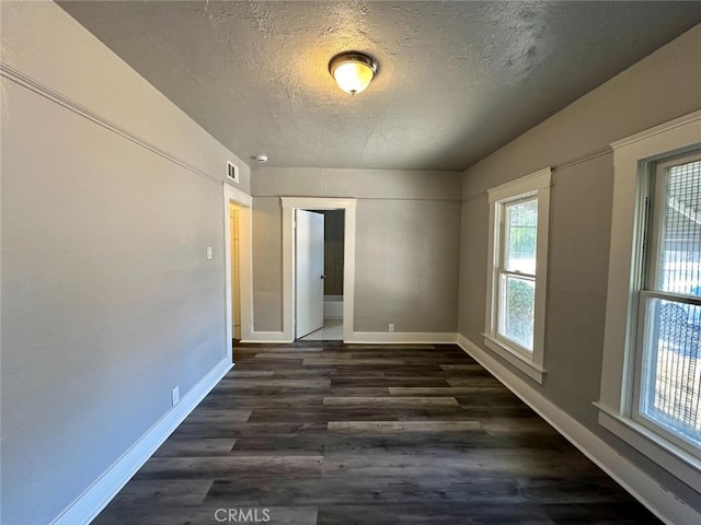 unfurnished room featuring a textured ceiling and dark hardwood / wood-style floors