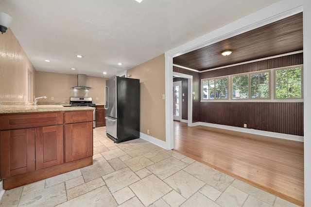 kitchen featuring sink, appliances with stainless steel finishes, wall chimney exhaust hood, and light stone countertops