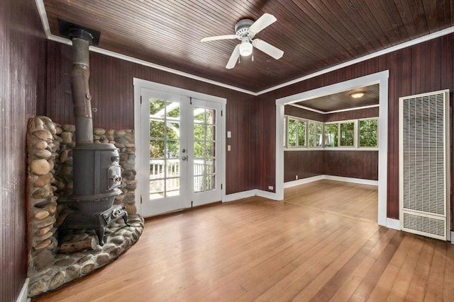 doorway with ceiling fan, a healthy amount of sunlight, a wood stove, and ornamental molding