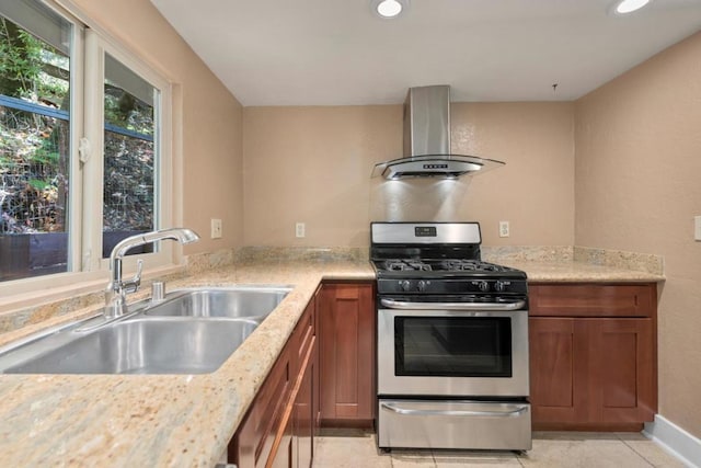 kitchen with light stone countertops, sink, wall chimney exhaust hood, and gas stove