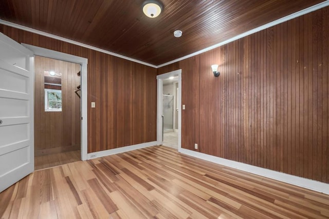 unfurnished room with light wood-type flooring, wooden ceiling, crown molding, and wooden walls