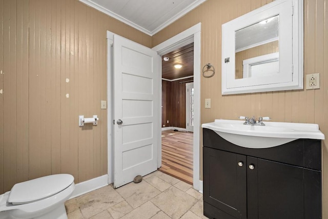 bathroom featuring wood walls, toilet, vanity, and crown molding