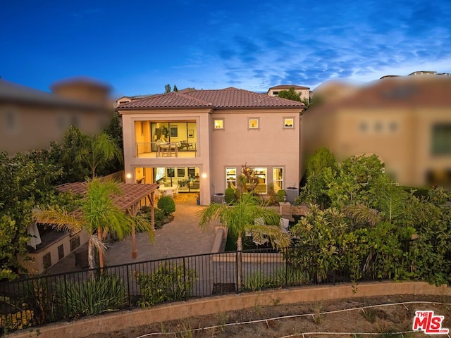 back house at dusk with a balcony