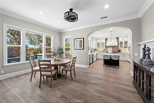 dining room with sink, light hardwood / wood-style flooring, and ornamental molding