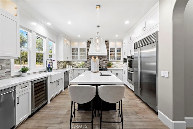 kitchen featuring a center island, wine cooler, light hardwood / wood-style flooring, appliances with stainless steel finishes, and white cabinetry