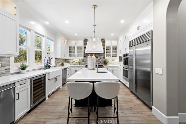 kitchen featuring appliances with stainless steel finishes, white cabinetry, a kitchen breakfast bar, a center island, and beverage cooler