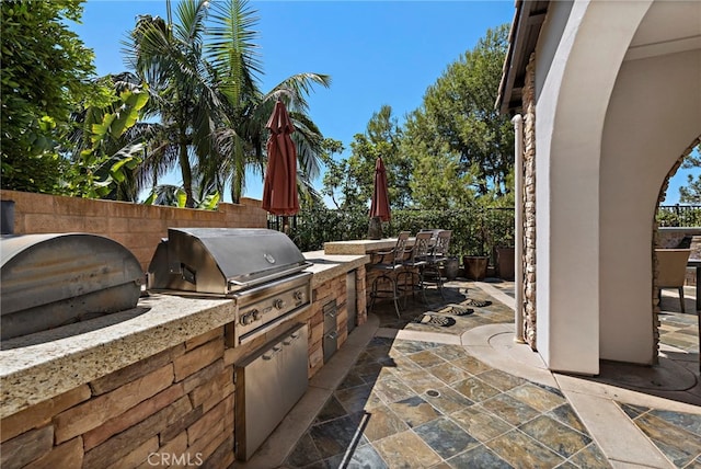 view of patio featuring a bar, an outdoor kitchen, and a grill