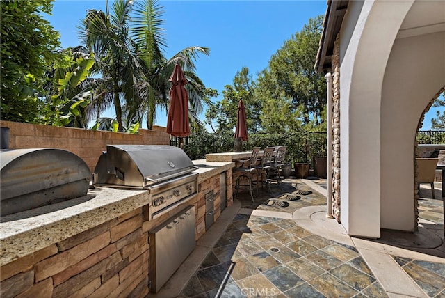 view of patio with exterior bar, a grill, and an outdoor kitchen