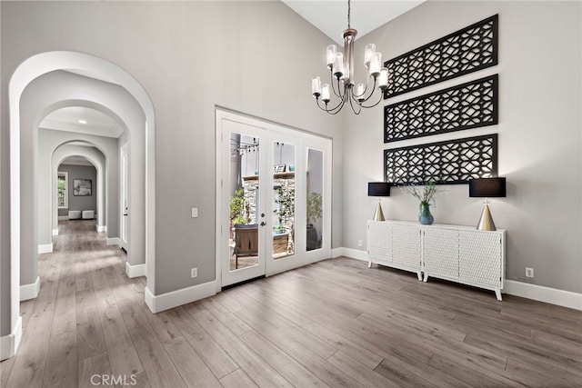 entrance foyer with baseboards, a high ceiling, arched walkways, and wood finished floors