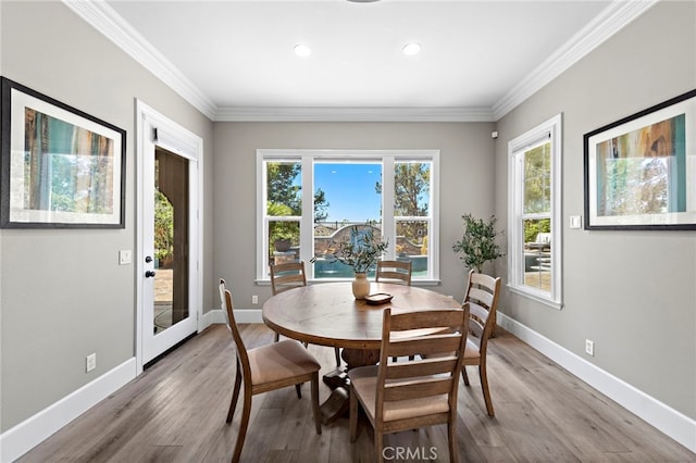 dining space with crown molding and light wood-type flooring