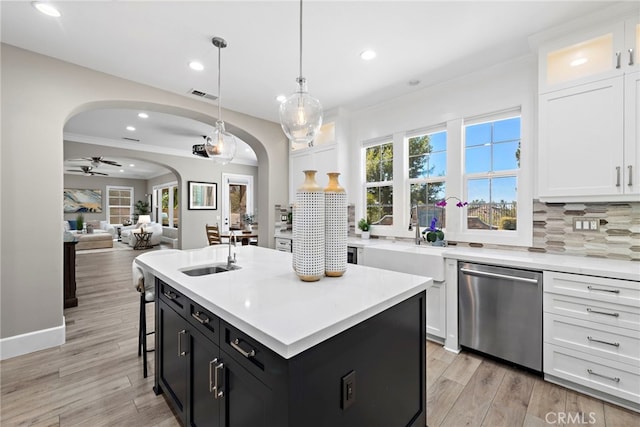 kitchen with decorative light fixtures, dishwasher, sink, white cabinets, and a kitchen island with sink