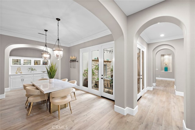 dining room with light hardwood / wood-style flooring, ornamental molding, and french doors