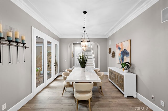 dining room with crown molding, wood-type flooring, a chandelier, and french doors