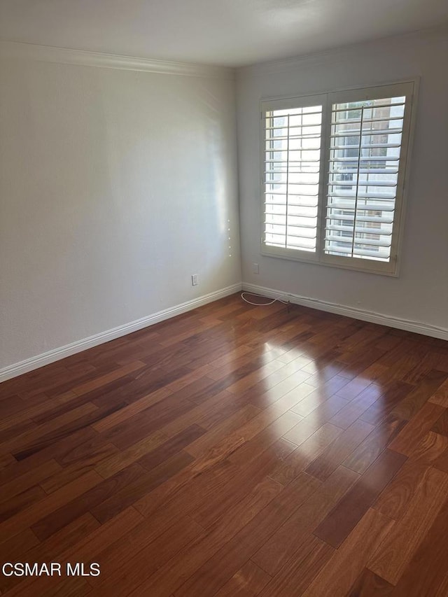 empty room featuring ornamental molding and dark wood-type flooring