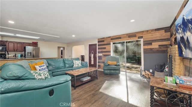 living room with wood walls, light wood-type flooring, and sink