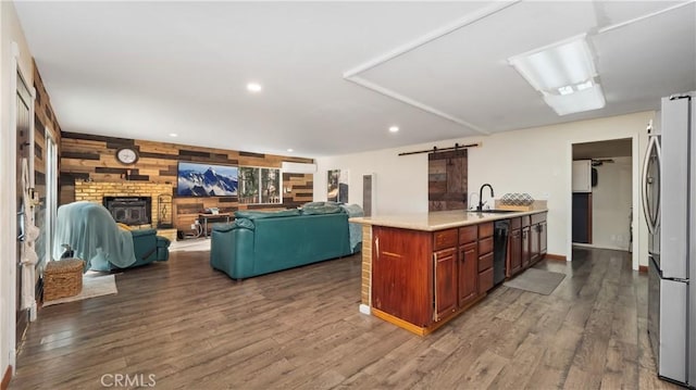 kitchen with stainless steel refrigerator, black dishwasher, a barn door, and hardwood / wood-style flooring