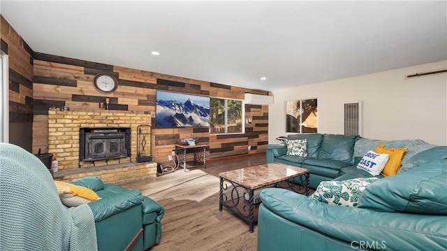 living room with light hardwood / wood-style floors, a wood stove, and wooden walls