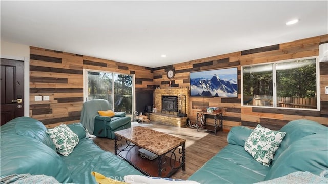 living room with a wood stove, wood walls, and a healthy amount of sunlight