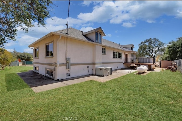 rear view of house featuring a wooden deck and a lawn