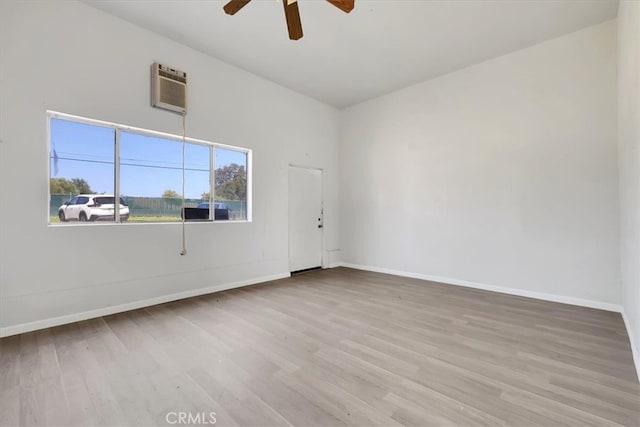 spare room featuring ceiling fan, light wood-type flooring, and a wall unit AC