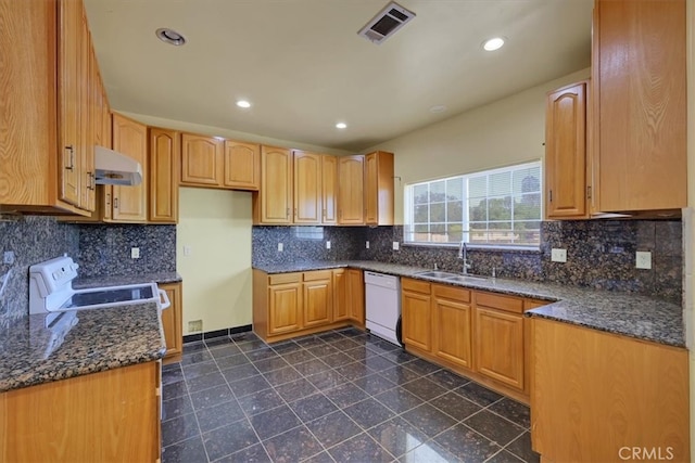 kitchen with decorative backsplash, white appliances, dark stone countertops, and sink