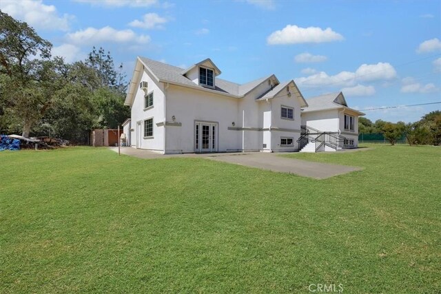 rear view of property featuring a patio, a yard, and french doors