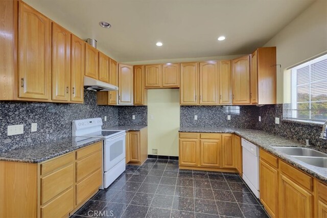 kitchen with decorative backsplash, white appliances, dark stone countertops, and sink