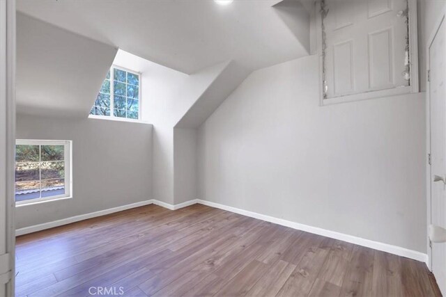 additional living space featuring light hardwood / wood-style floors and lofted ceiling