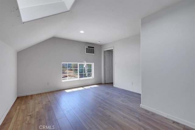 interior space featuring light hardwood / wood-style floors, lofted ceiling with skylight, and a wall mounted AC