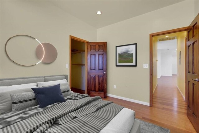 bedroom featuring light wood-type flooring, a closet, and a walk in closet