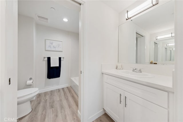 bathroom featuring wood-type flooring, vanity, toilet, and a tub